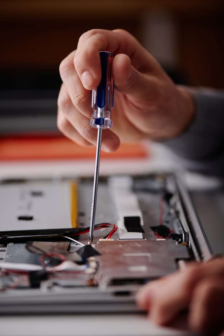 Tecnico con cacciavite ripara un computer portatile