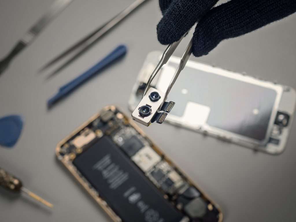 Tecnico ripara uno smartphone aperto sul banco di lavoro