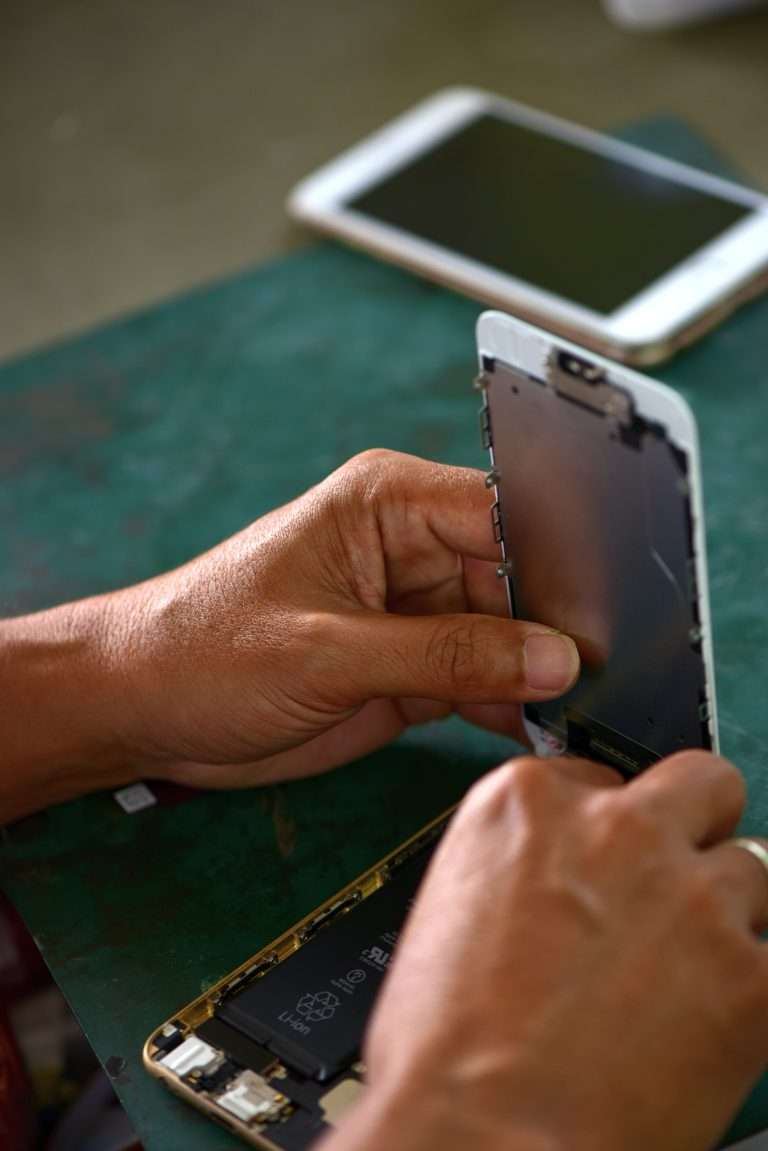 Mani di un tecnico che ripara un telefono cellulare