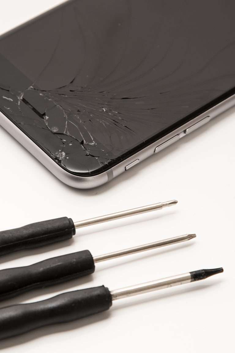 Smartphone con lo schermo rotto e cacciaviti di precisione per la riparazione
