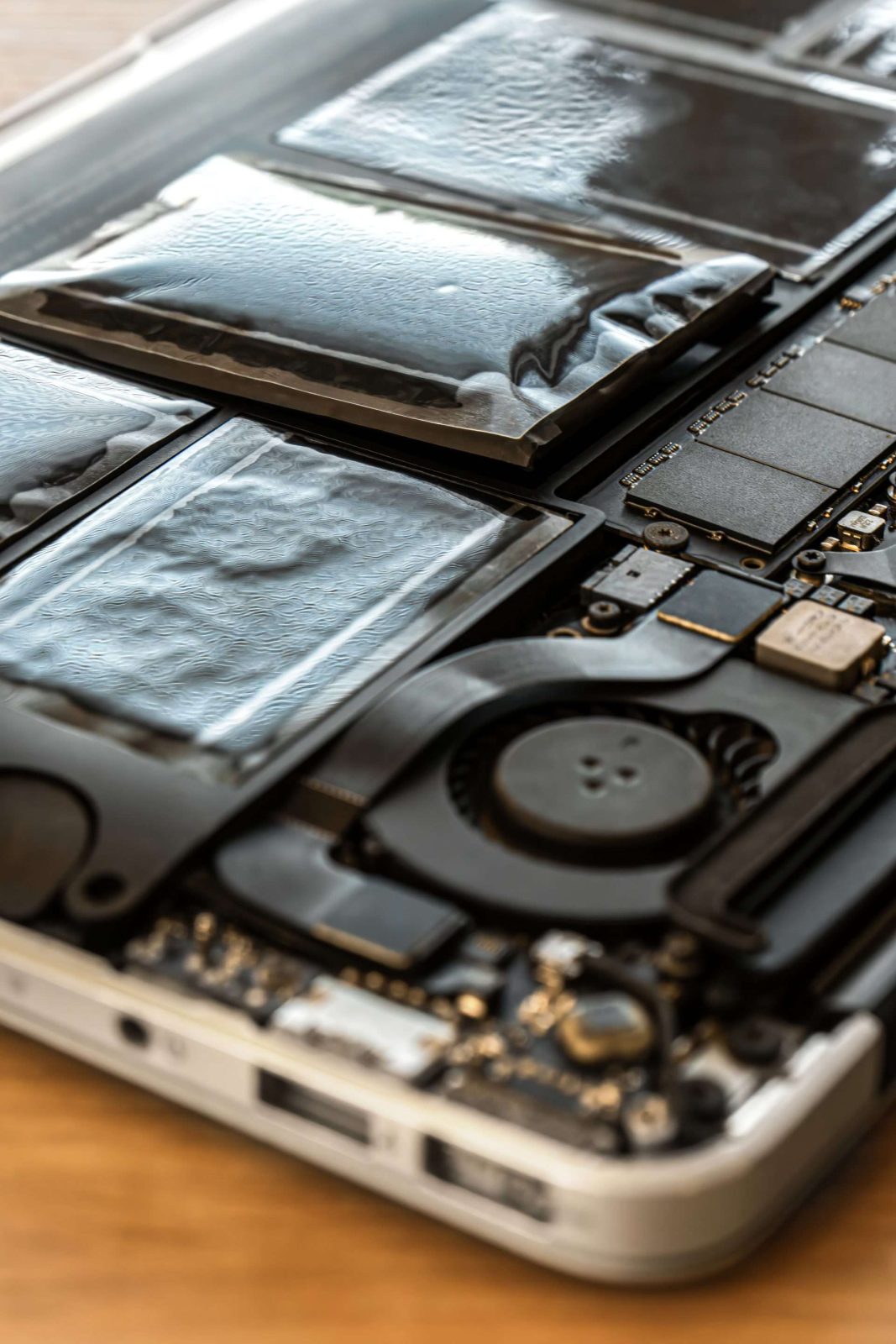 Swollen battery of broken laptop in open casing in repair service. Problem with pc closeup